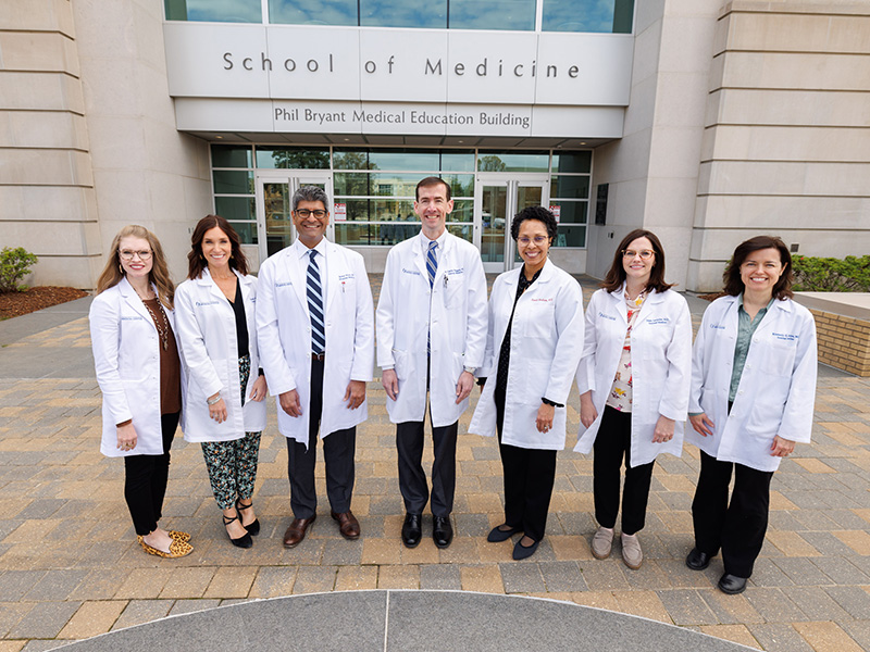 Seven program leaders standing in front of the School of Medicine.